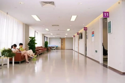 Bright hospital corridor with numbered exam rooms, brown sofas and potted plants at Shanghai — health screening for expats