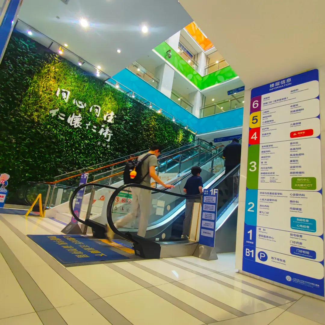 Outpatient atrium inside Shanghai Tongren Hospital with central escalator and full floor directory from B1 to 6F, helping visitors navigate the screening route