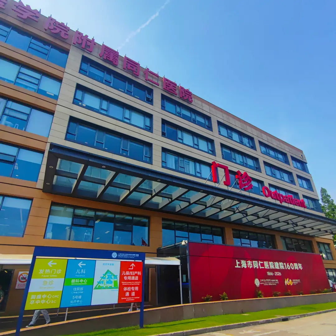 Outpatient building exterior of Shanghai Tongren Hospital with bilingual signage and 160th anniversary display, where international visitors arrive for health screening